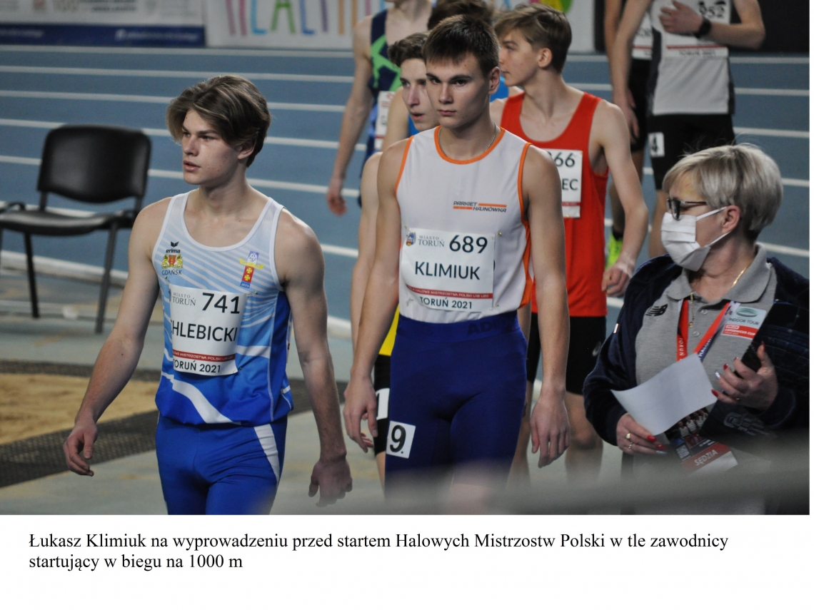 Łukasz Klimiuk na wyprowadzeniu przed staretem Halowych Mistrzostw Polski w tle zawodnicy startujący w biegu na 1000 m