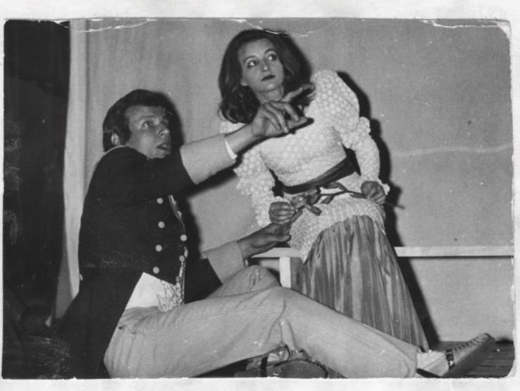 zdjęcie czarno-białe dwójki aktorów w scenie ze spektaklu "Kordian"; mężczyzna siedzi na podłodze i wskazuje na coś palcem; kobieta przy nim klęczy, patrząc w tym samym kierunku co on