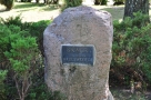zdjęcie przedstawia kamień z zamontowaną na nim tabliczką zawierającą napis Skwer im. Dymitra Wasilewskiego; wokół rosną niewysokie iglaste krzaki