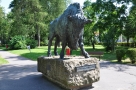 zdjęcie przedstawia pomnik żubra - wykonana z brązu figura żubra dużej wilkosci ustawiona na kamiennym cokole, z umiejscowioną tabliczką z napisem Żubr Imperator; w tle alejki parku i zieleń drzew oraz trawy