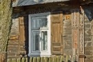 zdjęcie przedstawia fragment starej drewnianej chaty z oknem 