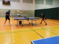 sala gimnastyczna, na pierwszym planie dwaj mężczyźni grający w tenisa stołowego 