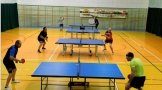 sala gimnastyczna, cztery stoły ustawione w rzędzie do gry w tenisa stołowego, przy każdym z nich po dwóch grających mężczyzn 