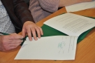 Na zdjęciu dłonie mężczyzny podpisującego dokument.