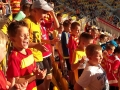 Dzieci w czerwono - żółtych strojach kibicują drużynie.