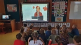 Przedszkolaki siedzą przed ekranem, na którym trwa projekcja filmu.