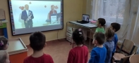 Przedszkolaki stoją przed ekranem, na którym trwa projekcja filmu.