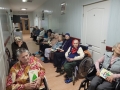 Seniorzy siedzą wzdłóż korytarza