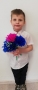 Chłopiec w eleganckiej koszuli trzyma kwiaty z bibuły.