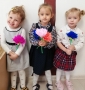 Trzy dziewczynki trzymają kwiaty z bibuły.