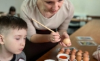 instruktorka pokazuje chłopcu jak dekorować jajko. 