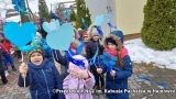 Dzieci ubrane w zimowe kurtki i czapki trzymaja niebieskie serca.