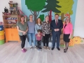 Na zdjęciu stoi sześć dorosłych osób i dziecko. Wśród nich - minister Jarosław Zieliński i dyrektor Dorota  Durzyńska. W tle widać salę przedszkolną.