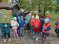 Dzieci stoją przed kontenerem i pozują wraz z nauczycielką do zdjęcia, trzymają w rękach gumowe rękawiczki i transparent z napisem: Kochaj Przyrodę!