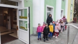 Dzieci z opiekunkami stoją przed wejściem do domu kultury