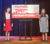dwie dziewczynki przy p[lanszy z tytułem festiwalu