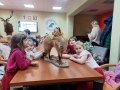 Dzieci siedzą przy stole, oglądają eksponaty leśnych zwierząt.