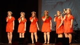 sześć dziewcząt w czerwonych sukienkach stoi na scenie