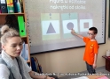 chłopiec pokazuje na tablicy figure w kształcie nagretki od słoika. Z lewej strony siedzi nauczyciel