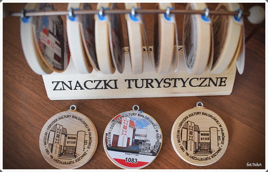 Na stole leżą trzy znaczki turystyczne. Dwa z tym samym wizerunkiem. 