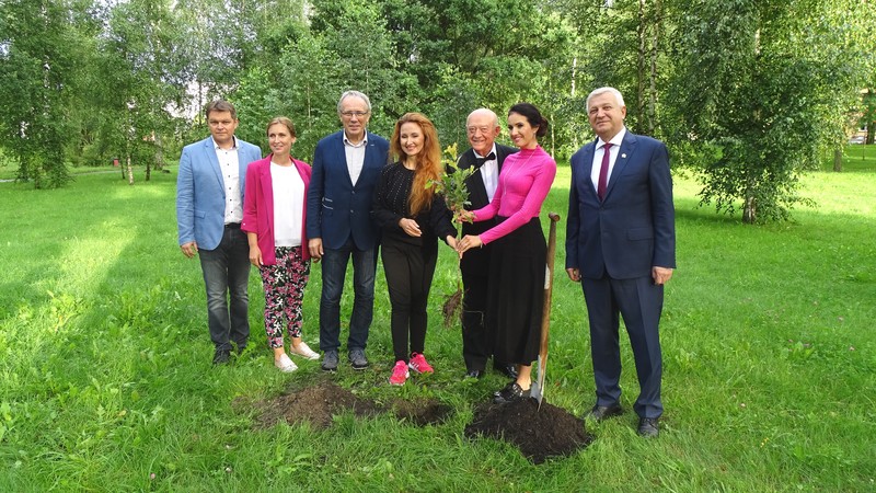 do pamiatkowego zdjecia pozuje 7 osób.  Trzy osoby rzymają wspólnie sadzonkę dębu.