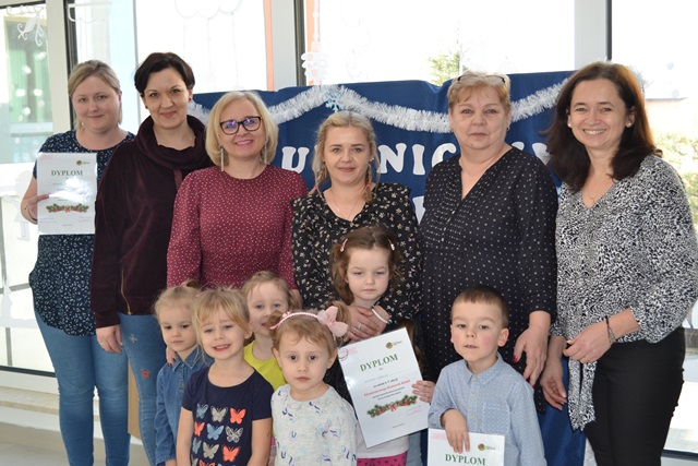 Zdjęcie przedstawia grupowe ustawienie uczestników Ekumenicznego Koncertu Kolęd: dzieci, pani dyrektor oraz panie nauczycielki.