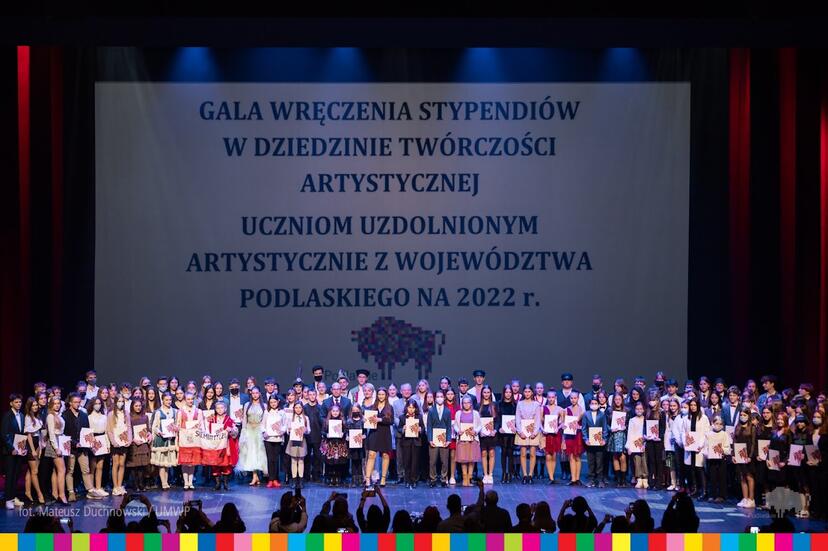 Pamiątkowe zdjęcie dużej grupy stypendyst&oacute;w. W tle widać logo Wojew&oacute;dztwa Podlaskiego.