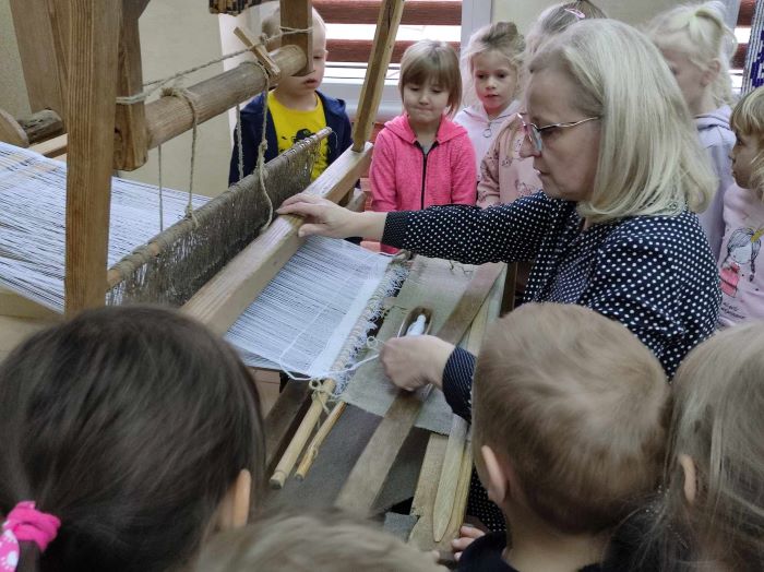 kobieta pokazuje dzieciom tkanie dywanów