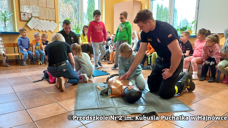 mężczyzna pokazuje dzieciom na manekinie zasady udzielania pomocy