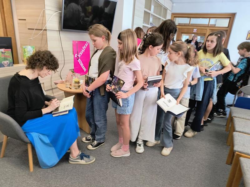 kobieta składa dzieciom autografy