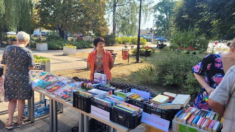 kilka osób przy długim stole z książkami na sprzedaż. 