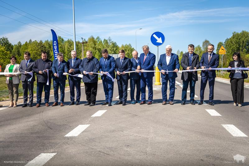 czternaście osób stoi na drodze i przecina wstęgię