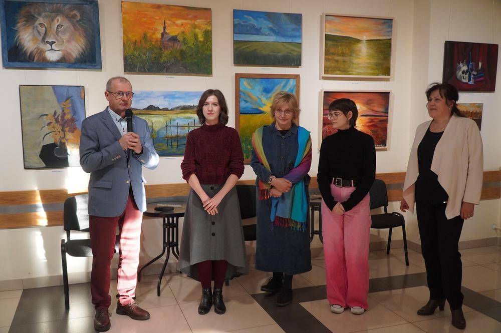 artyści podczas otwarcia wernisażu. W tle widać wystawę ich prac