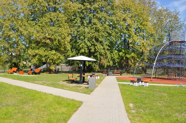 ścieżki na placu zabaw, w oddali ławka i stolik z możliwością połaczenia wifi