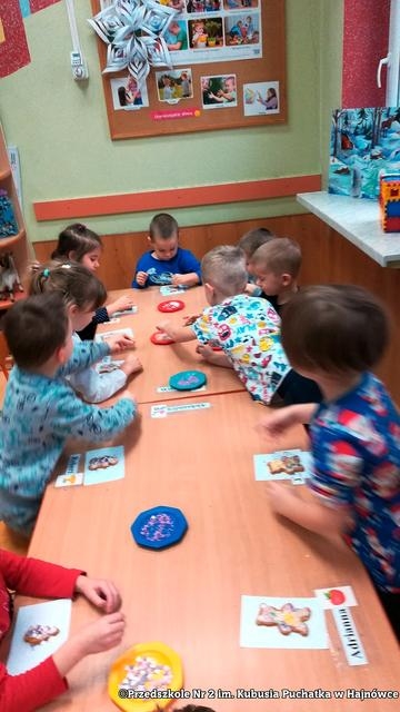 Na zdjęciu dzieci ozdabiają pierniczki polane polewą lukrową.