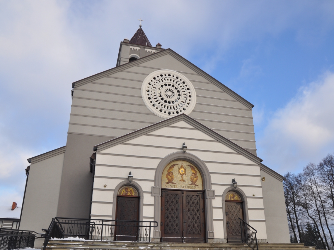 kościół przyklasztorny w kolorze szarym, u góry nad wejściem widnieje tzw. rozeta, obok wejścia głównego po stronie prawej i lewej jest dwoje mniejszych drzwi 