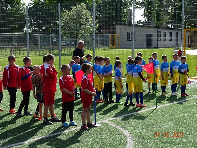 Dwie drużyny w strojach klubowych stoją na murawie stadionu