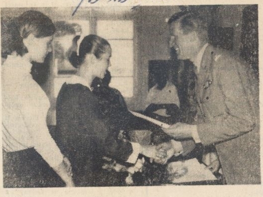 Na zdjęciu: przewodniczący komitetu rodzicielskiego Leopold Rzezak wręcza świadectwo szkolne przodującej uczennicy Teresie Pietraszko.[skan czarno-białego zdjęcia prasowego; na zdjęciu widoczne trzy osoby: po lewej dwie dziewczyny stojące jedna za drugą, po prawej mężczyzna; mężczyzna podaje rękę dziewczynie po prawej]