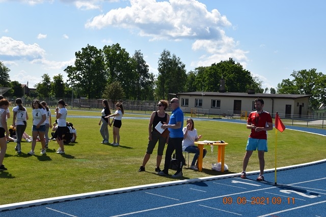 zawodnicy i sędziowie stoją na bieżni