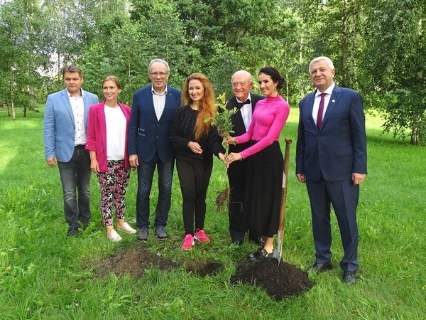 do pamiatkowego zdjecia pozuje 7 osób.  Trzy osoby rzymają wspólnie sadzonkę dębu.