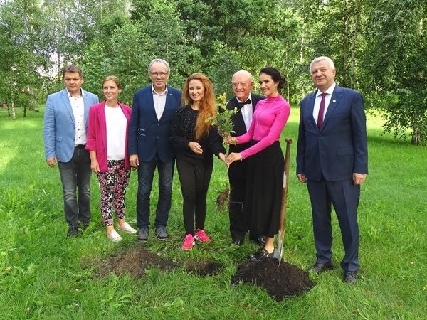 do pamiatkowego zdjecia pozuje 7 osób.  Trzy osoby rzymają wspólnie sadzonkę dębu.