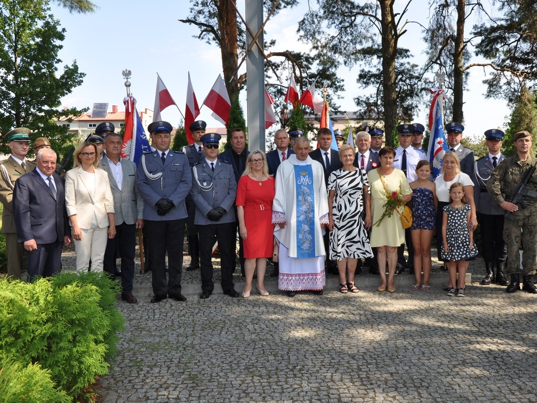 grupa ludzi stoi przed pomnikiem