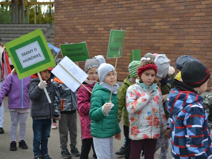 Dzieci idą z transparentami zachęcającymi do dbania o czystość w naszym mieście.