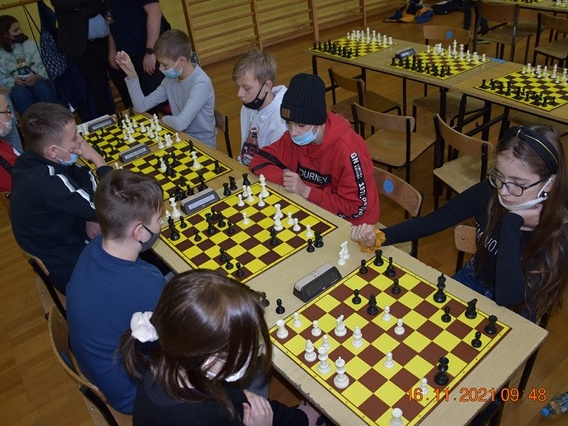 Młodzież grająca w szachy przy kilku stołach