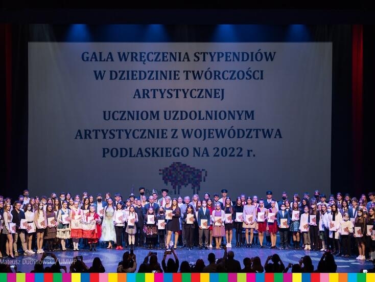 Pamiątkowe zdjęcie dużej grupy stypendystów. W tle widać logo Województwa Podlaskiego.