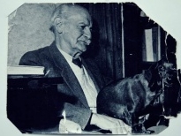 czarno-białe zdjecie przedstawiające dr Tadeusza Rakowieckiego głaszczącego czarnege zwierzę