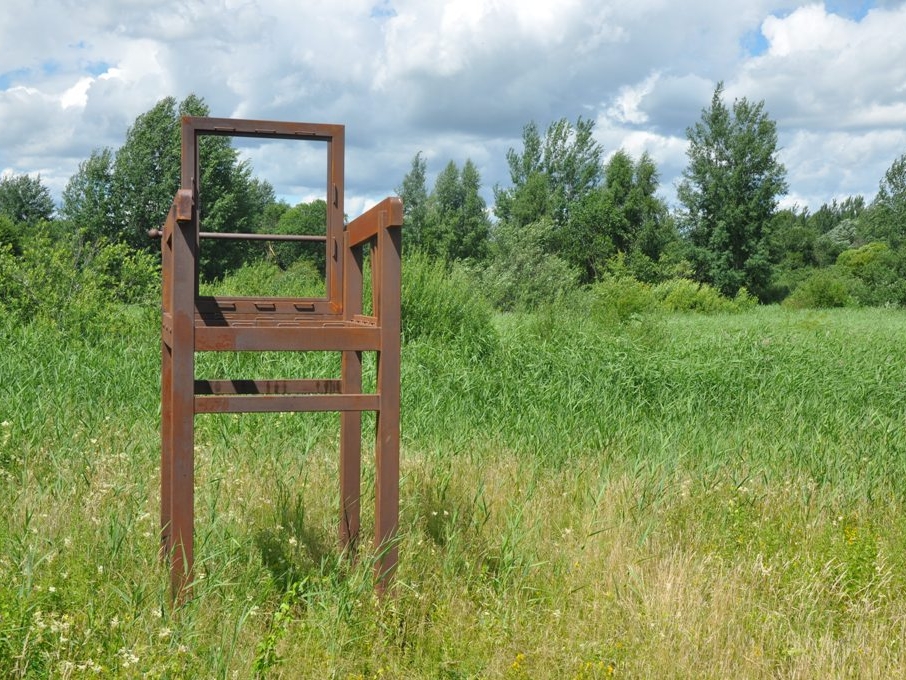 rzeźba w kształcie szkieltu fotela w otoczeniu zielonej trawy