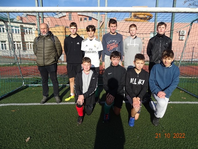 Grupa chłopców stoi przy bramce