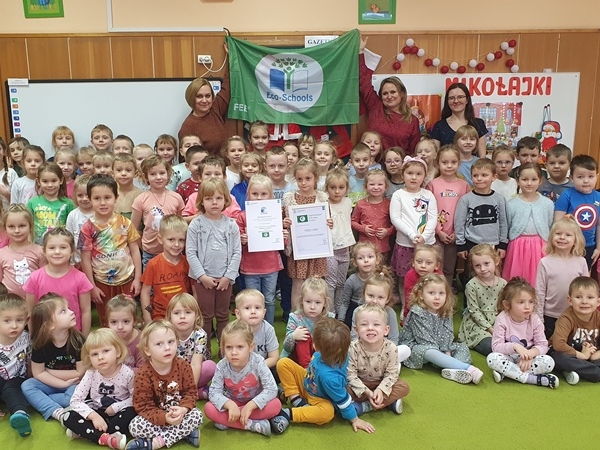 zdjęcie grupowe dzieci . Panie trzymają zielona flagę