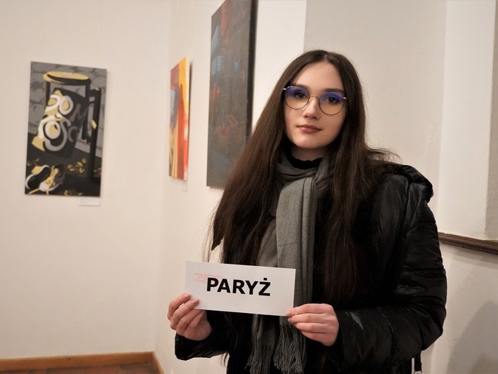młoda dziewczyna prezentuje kartkę z napisem PARYŻ
